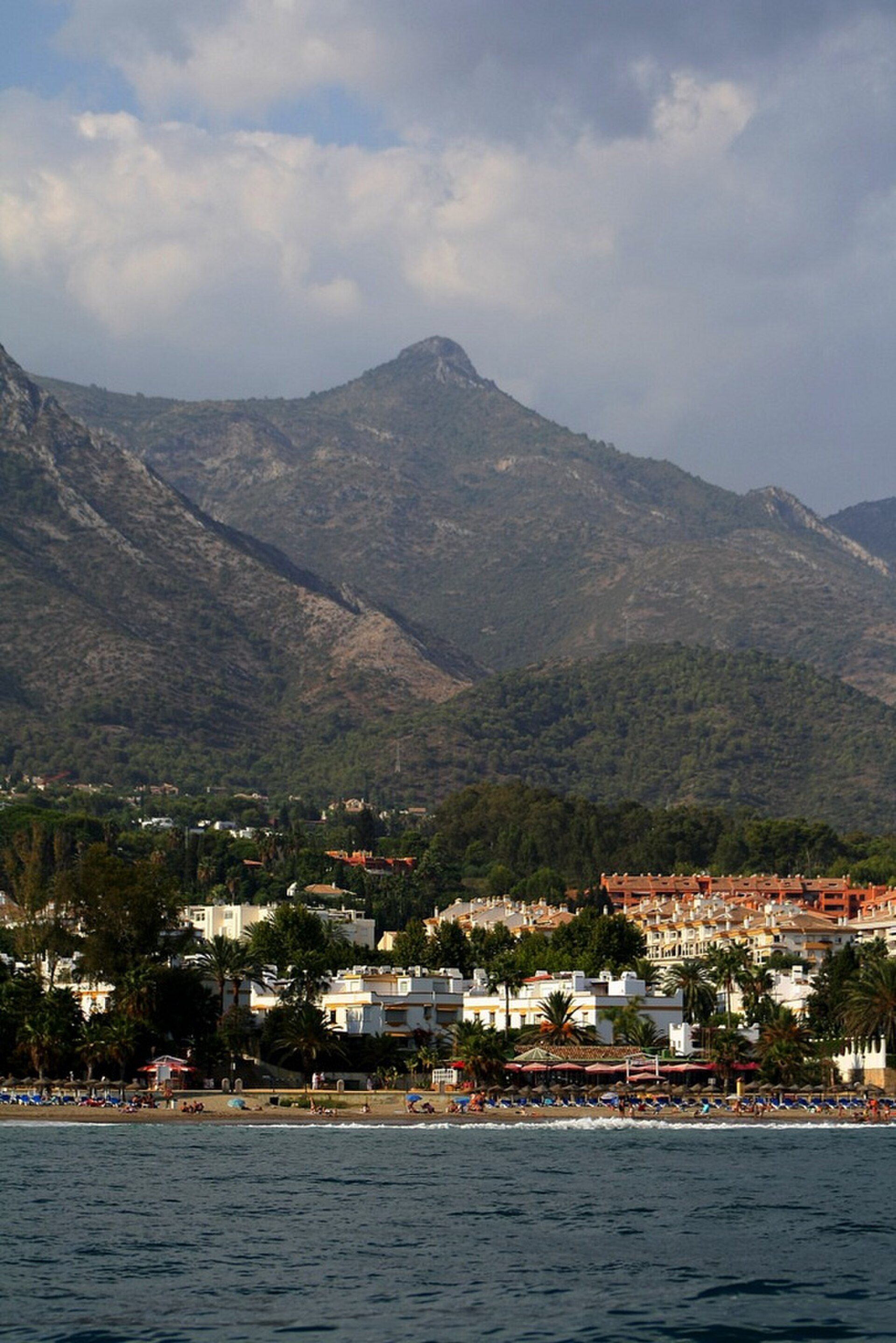 Cozy room with sea view, balcony, and mountain backdrop.