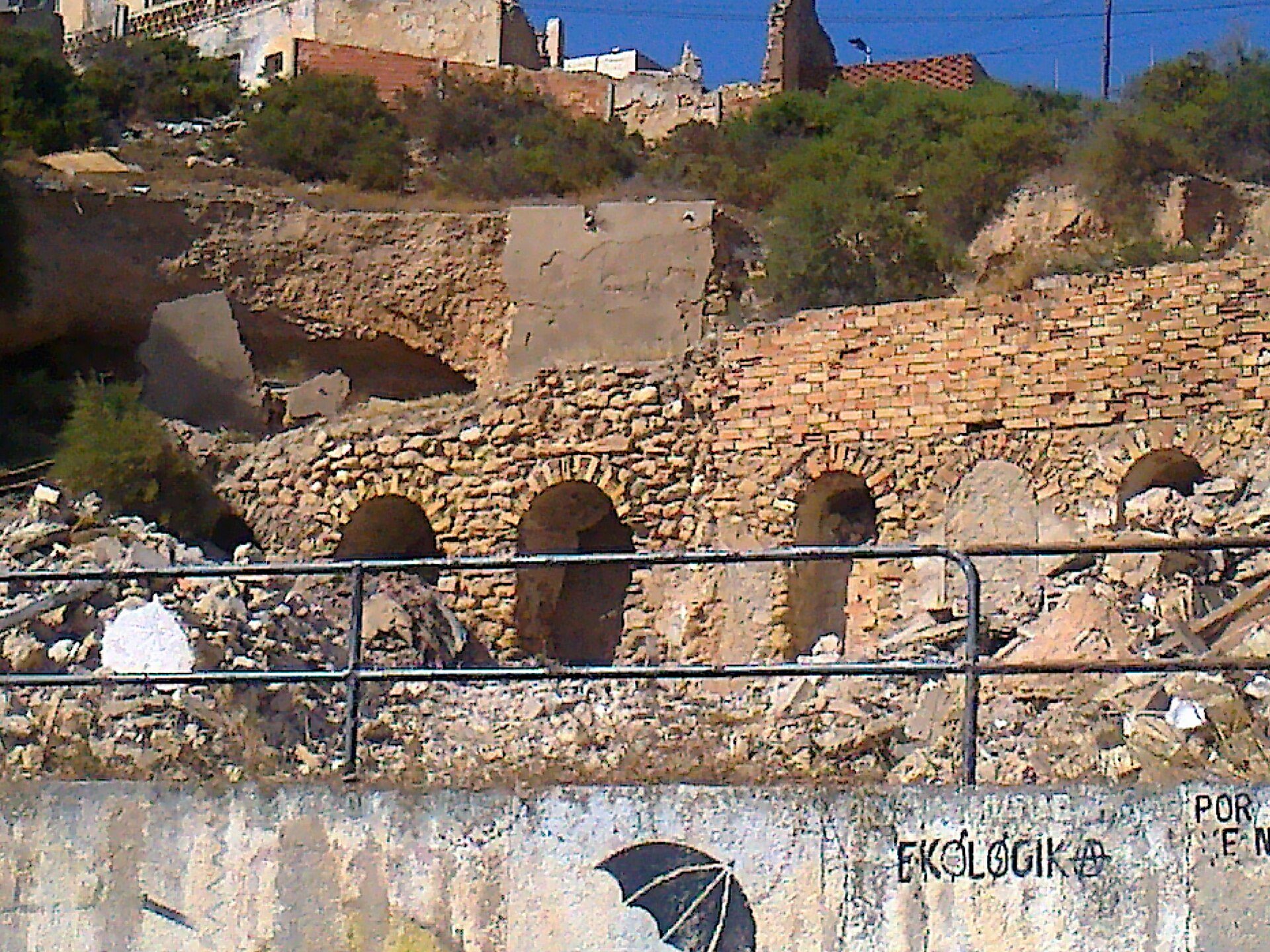 Old stone building with arched windows, overlooking a historic town.