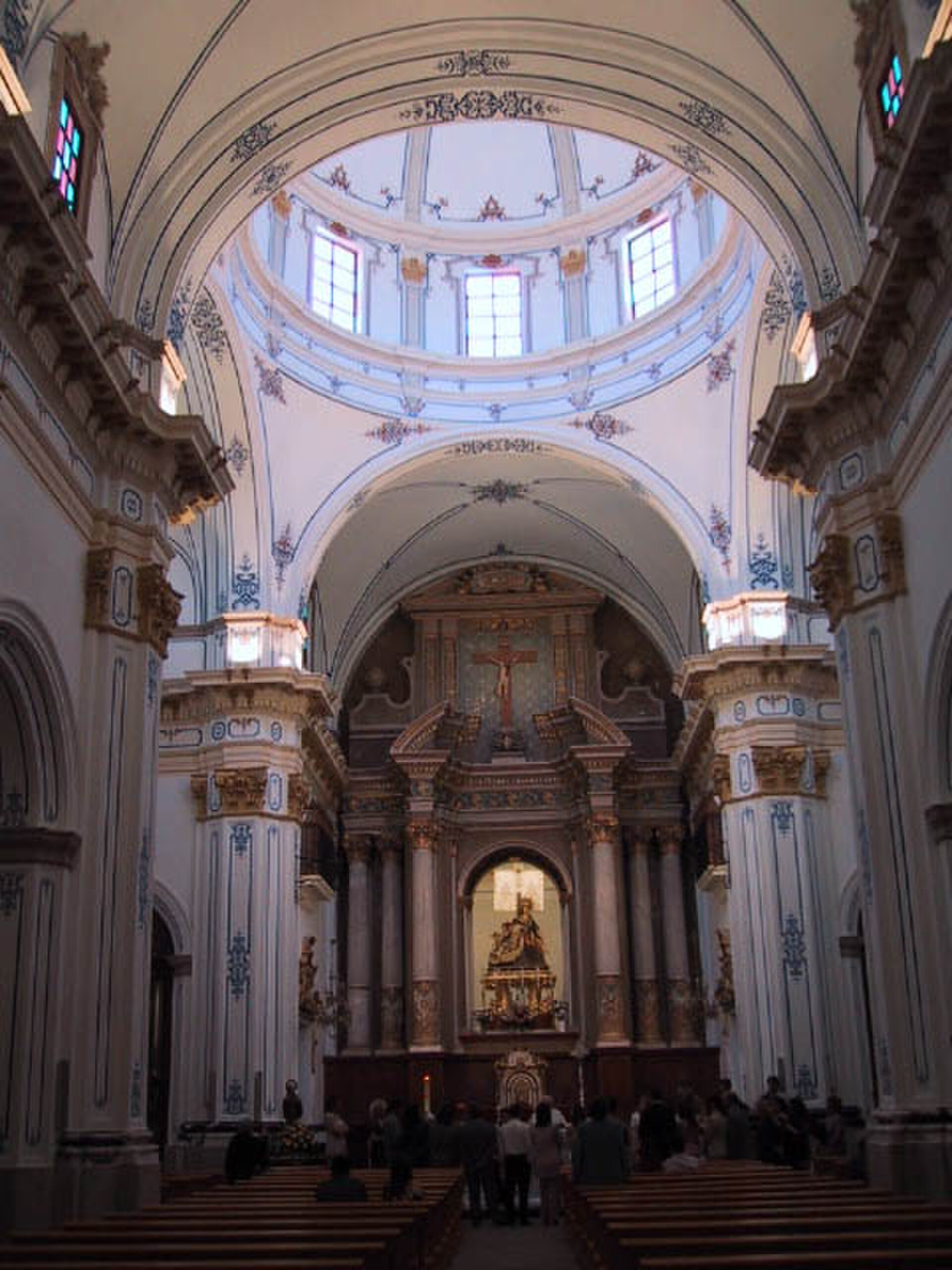 Interior view of a grand church with ornate decorations, high ceilings, and stained glass windows.