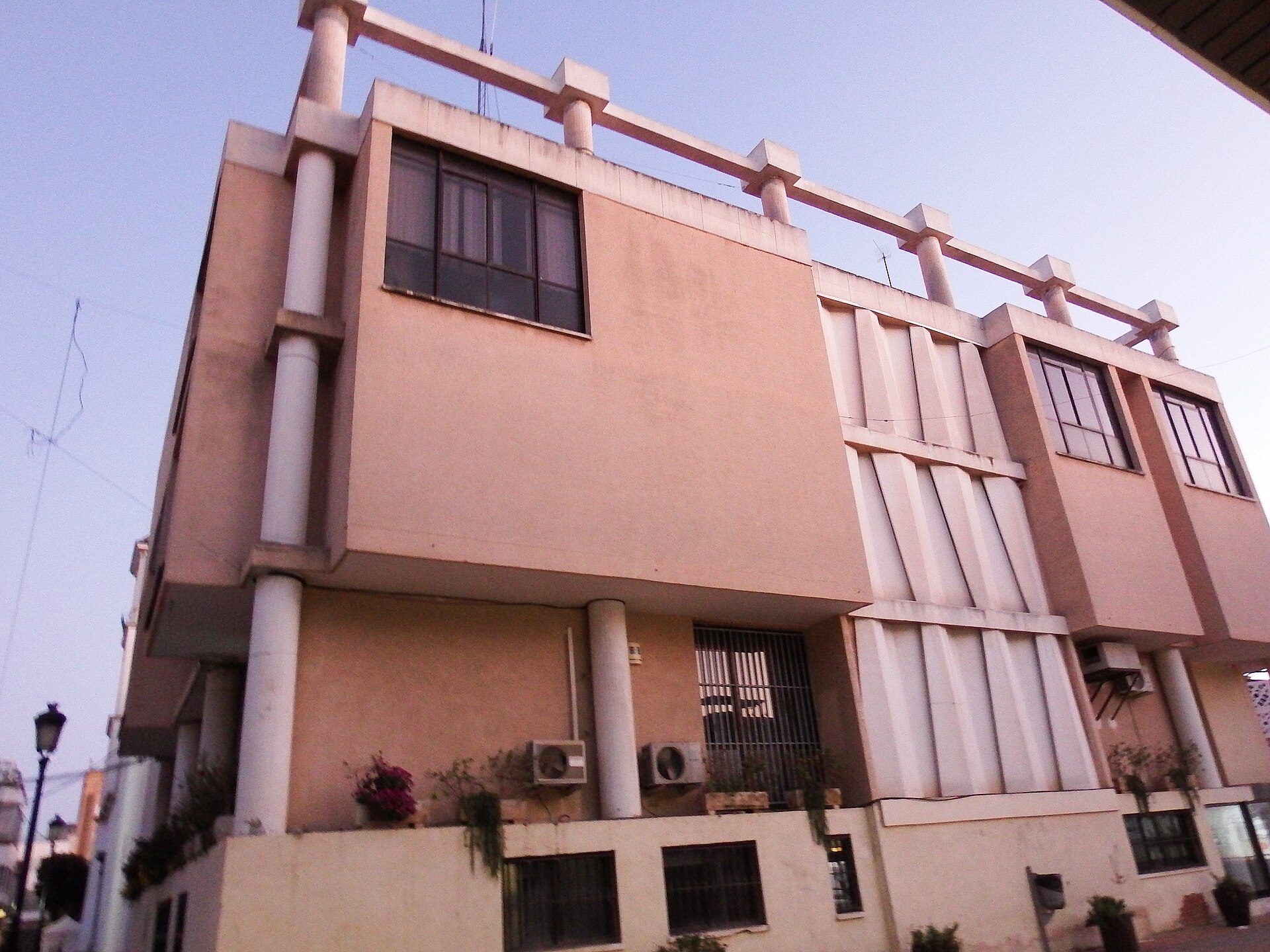 A modern two-story building with balconies, large windows, and air conditioning units.