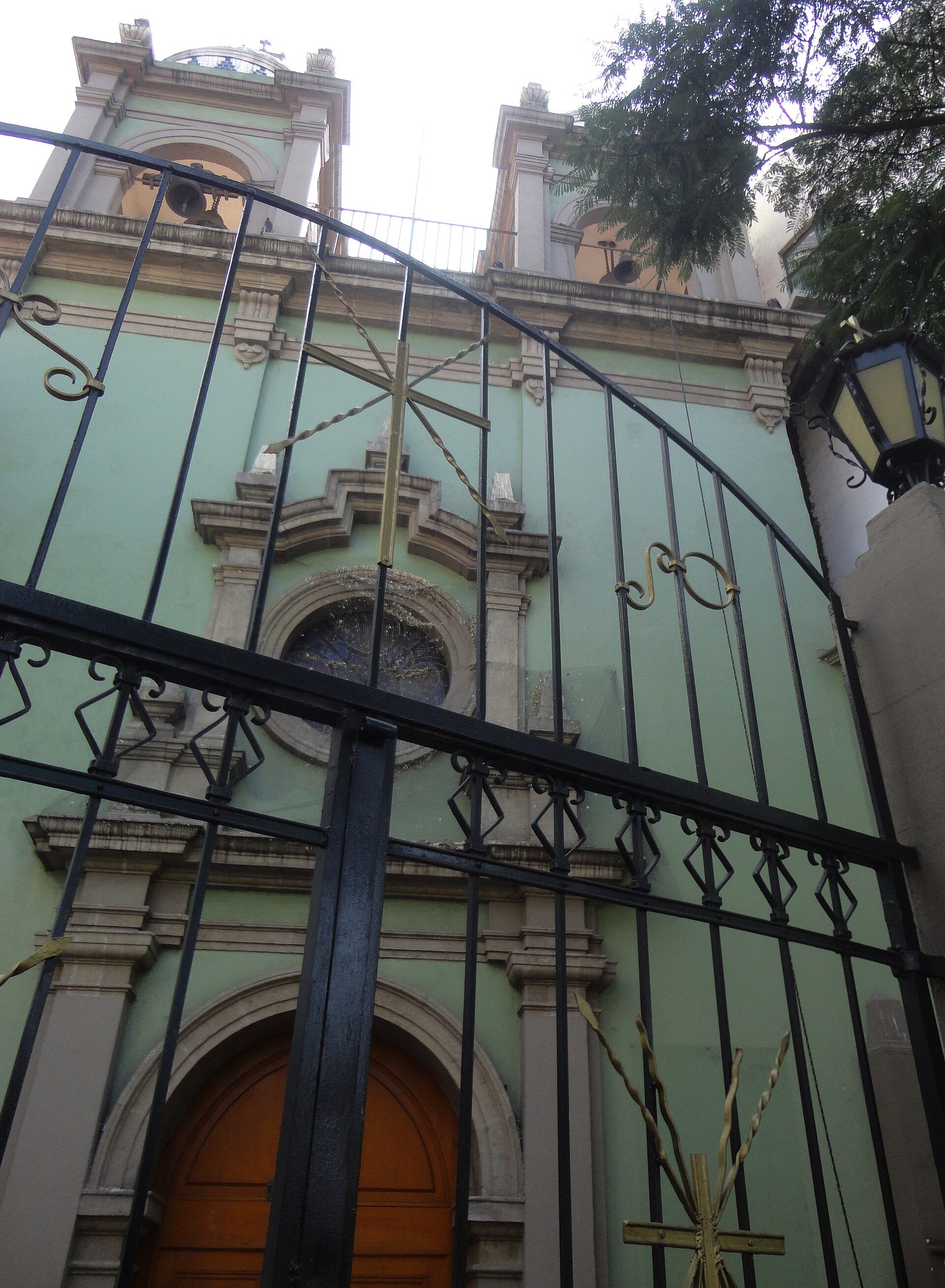 Alt text: Ornate church gate with intricate metalwork and a large wooden door.