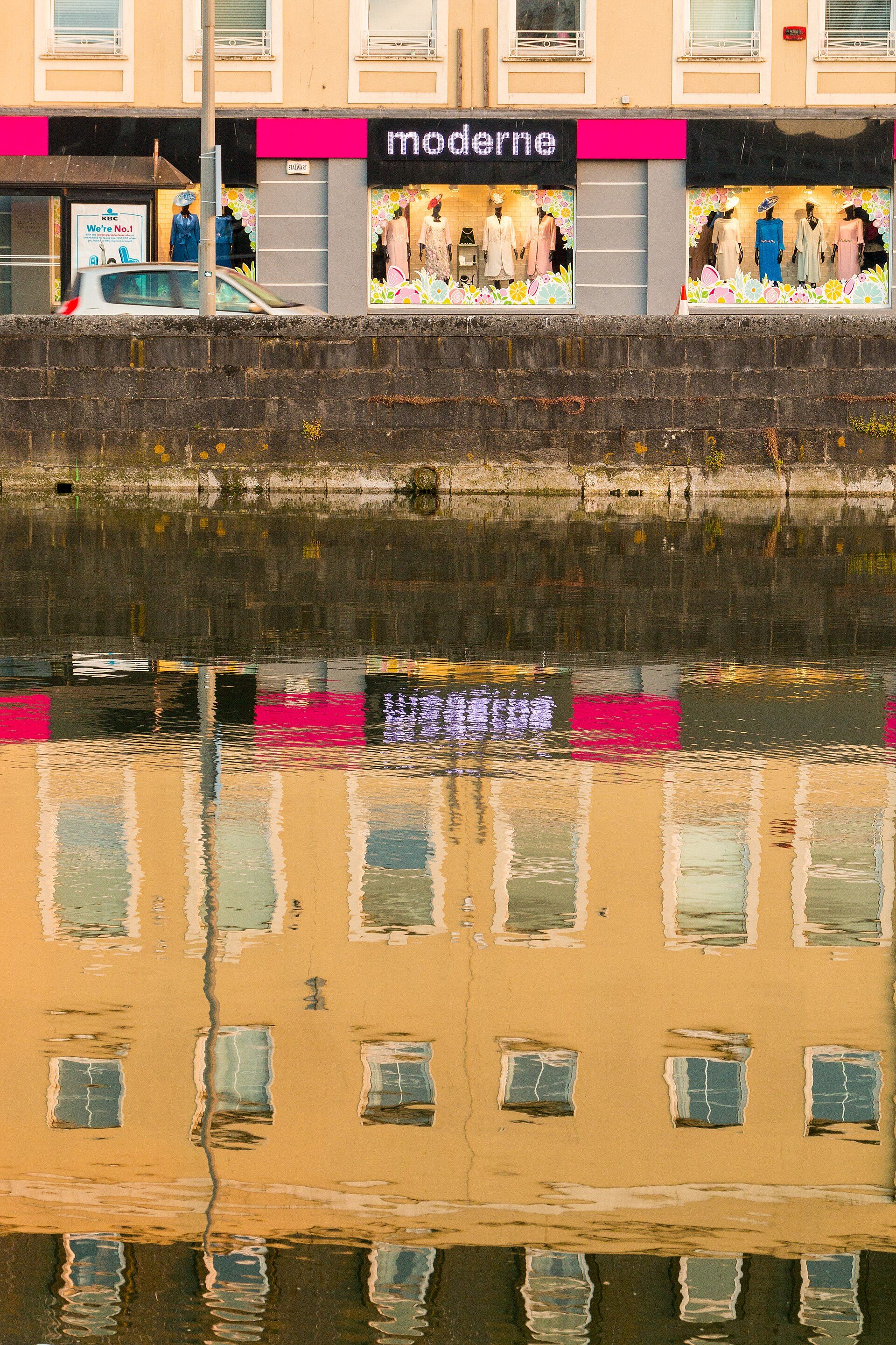 Alt text: Modern apartment with canal view, featuring large windows and a serene water reflection.