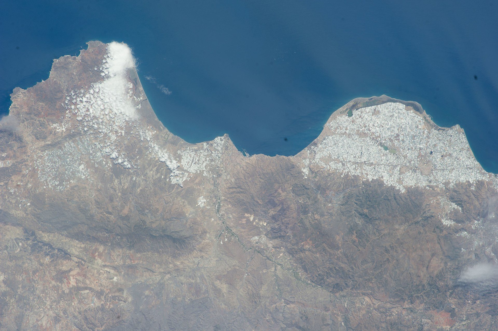 Aerial view of a coastal city with a mountainous landscape and ocean.