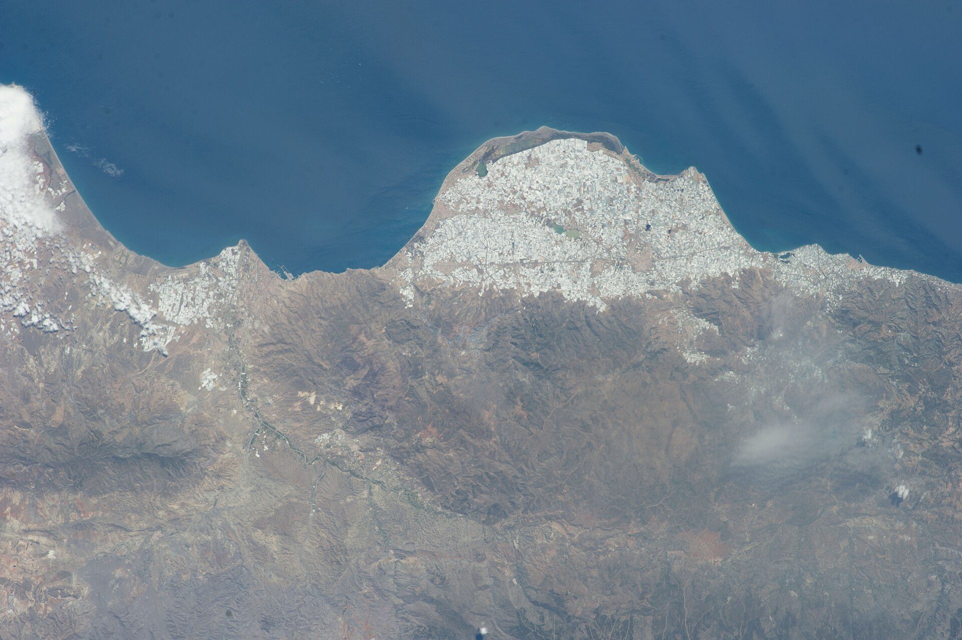 Aerial view of a coastal city with mountains and ocean.