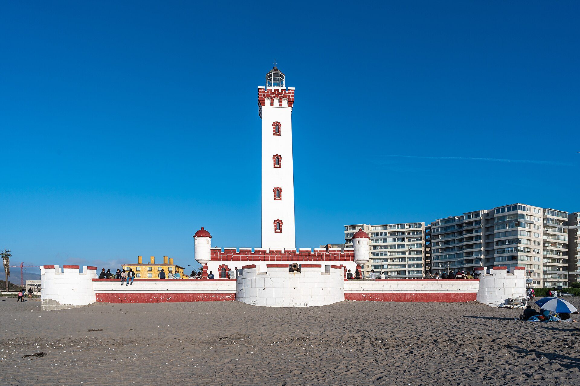 Alt text: Beachfront lighthouse with ocean view, featuring a tall white tower and red accents.