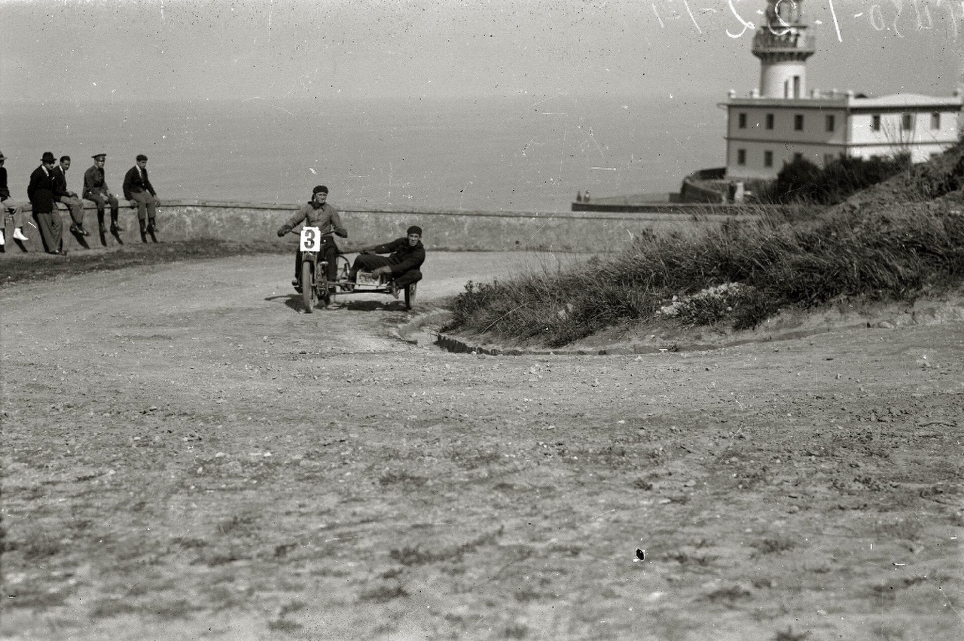 Alt text: Vintage photo of a coastal race with a lighthouse in the background.