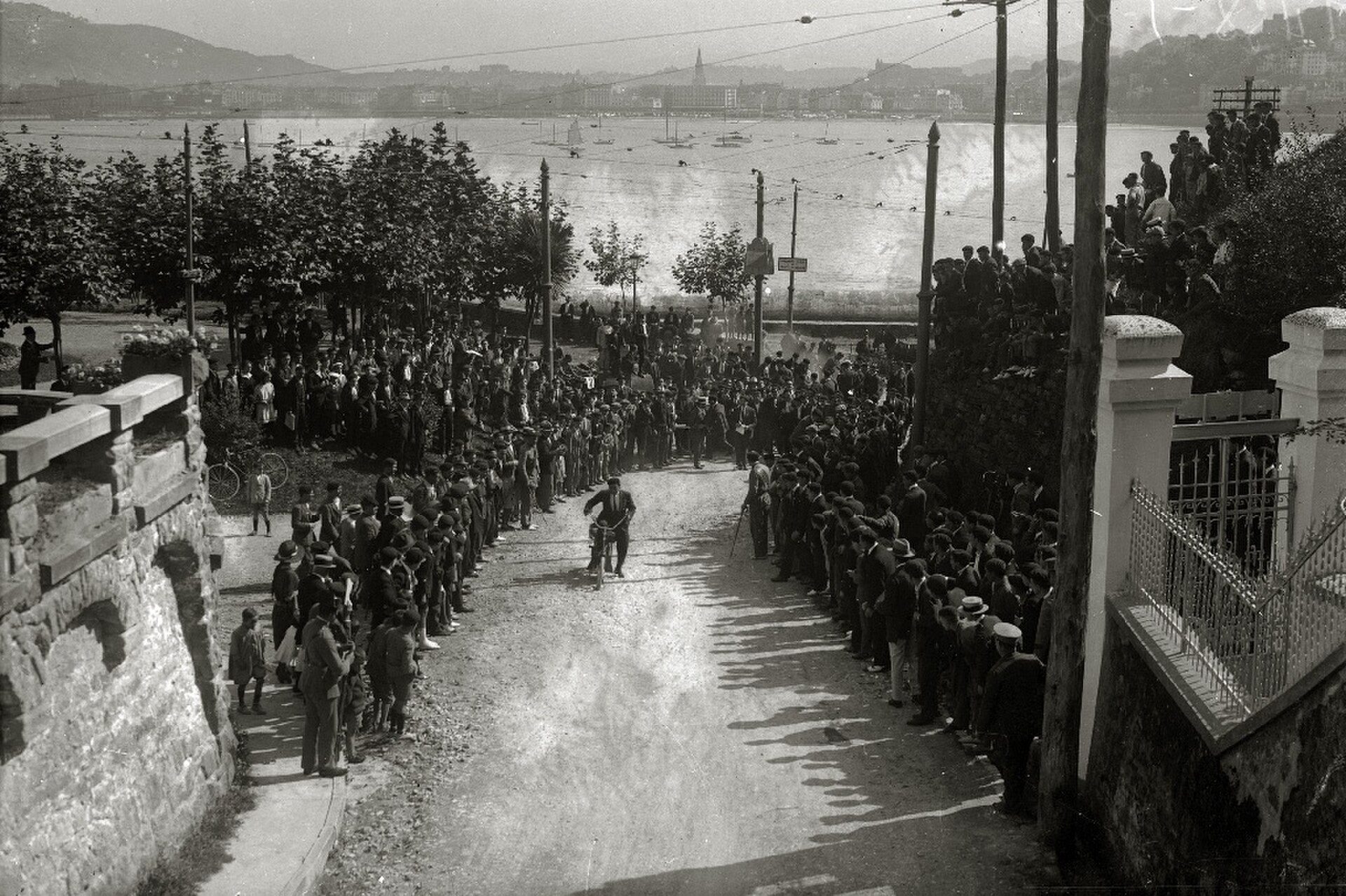 Alt text: Vintage black-and-white photo of a street race with spectators lining the road.