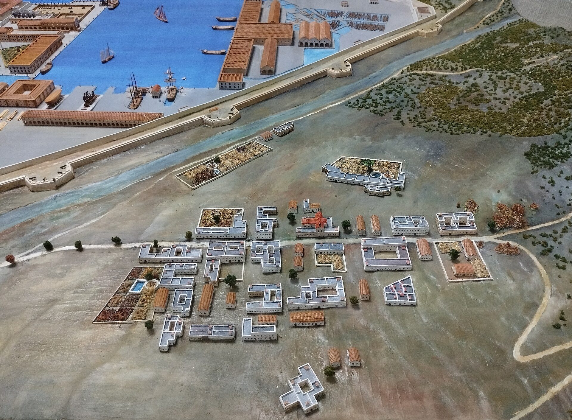 Aerial view of a coastal town with docks, boats, and Mediterranean-style buildings.