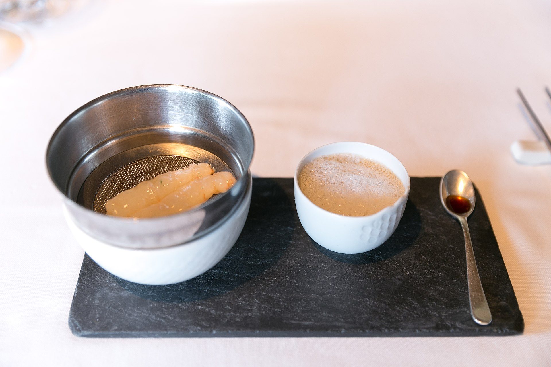 A meal setup on a tray with a fish dish, sauce, and utensils.