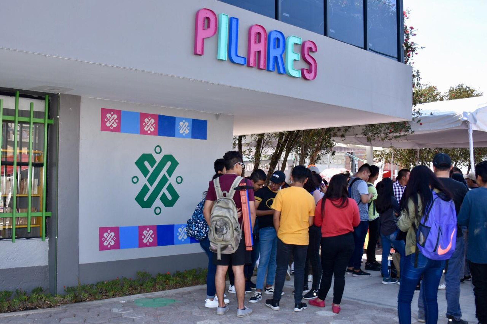 A group of people standing outside a building with colorful signage and a logo.