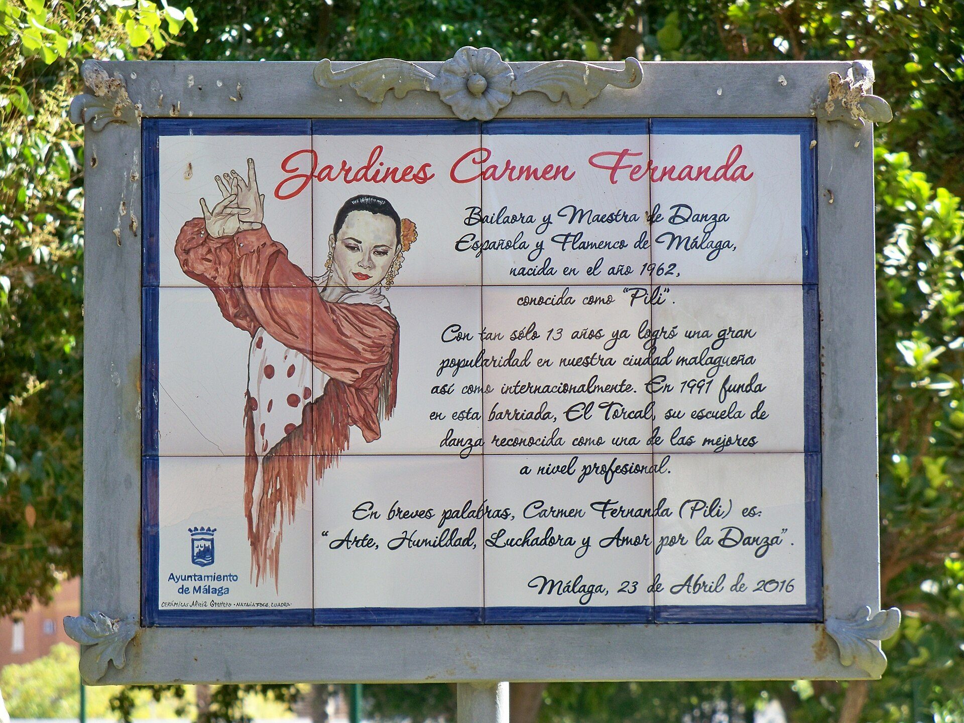 Sign for Carmen Fernanda Garden, featuring a woman illustration, text in Spanish, and a date.