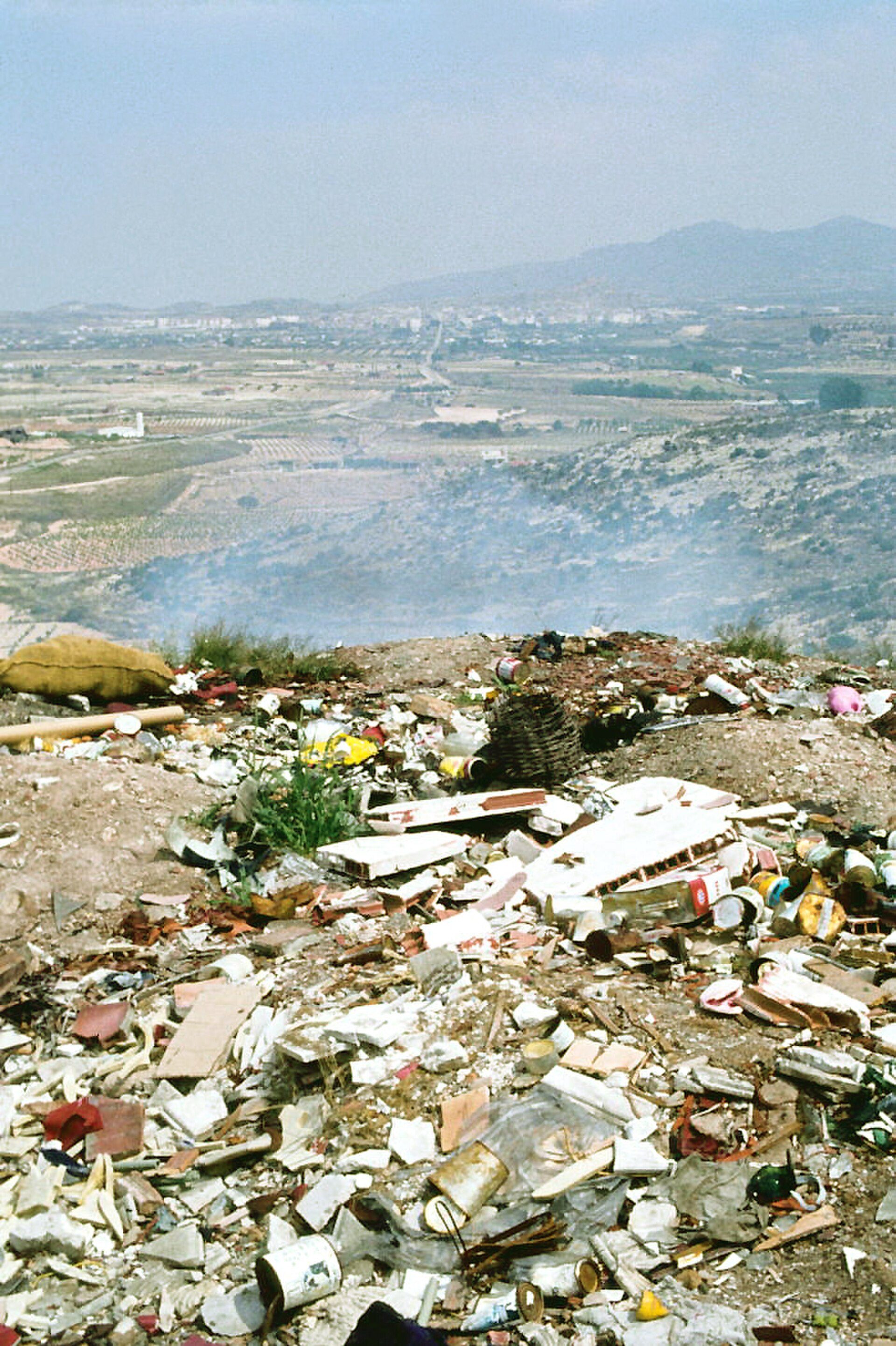 Alt text: Panoramic view of a landfill with scattered waste and distant landscape.