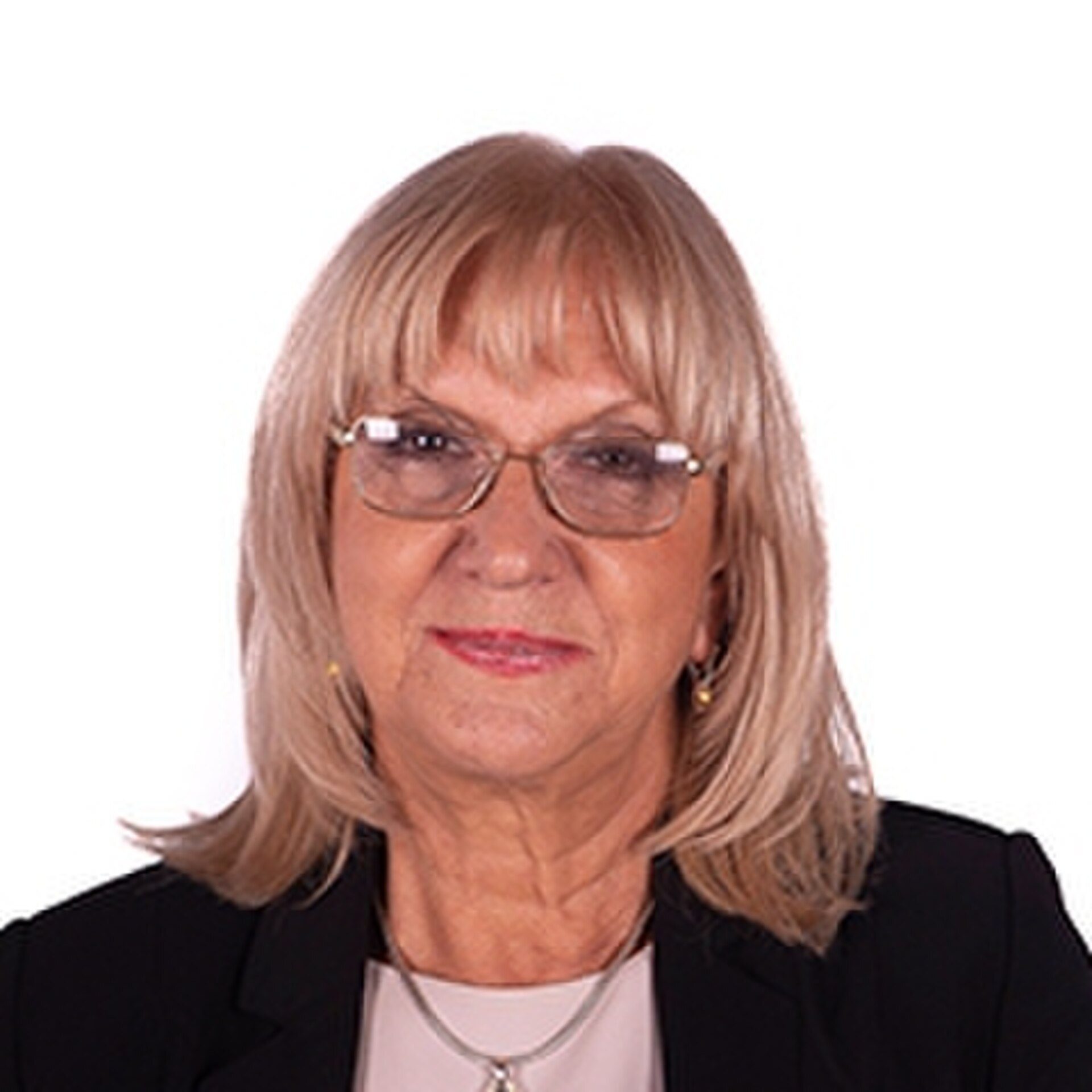 A woman with short blonde hair and glasses is wearing a black blazer.