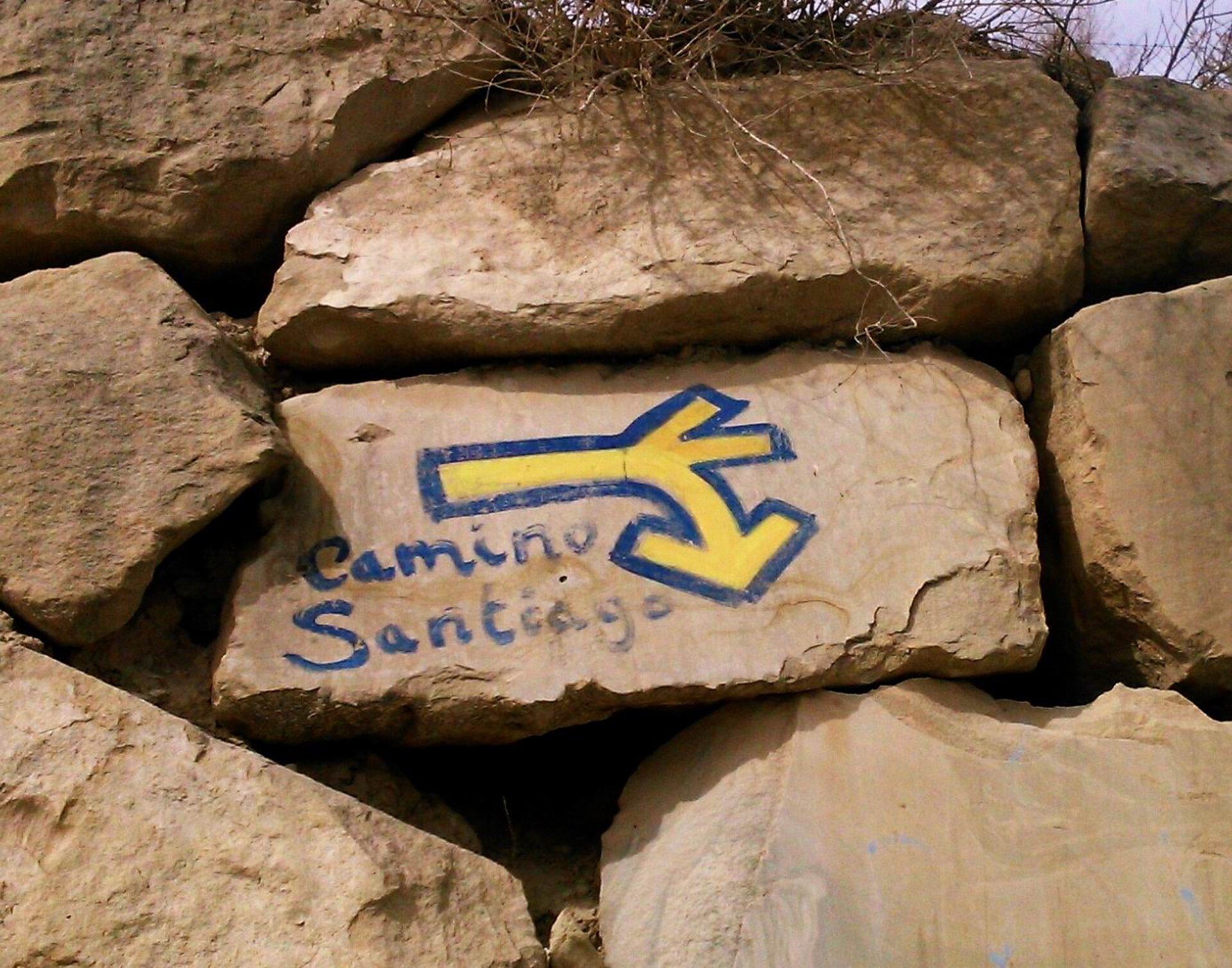 Alt text: Rock with directional arrow and "Camino Santiago" text.