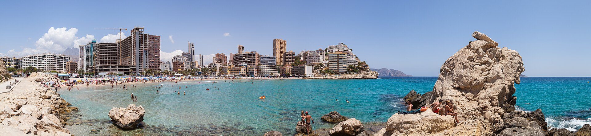 Sea view room with balcony, modern amenities, and city skyline.