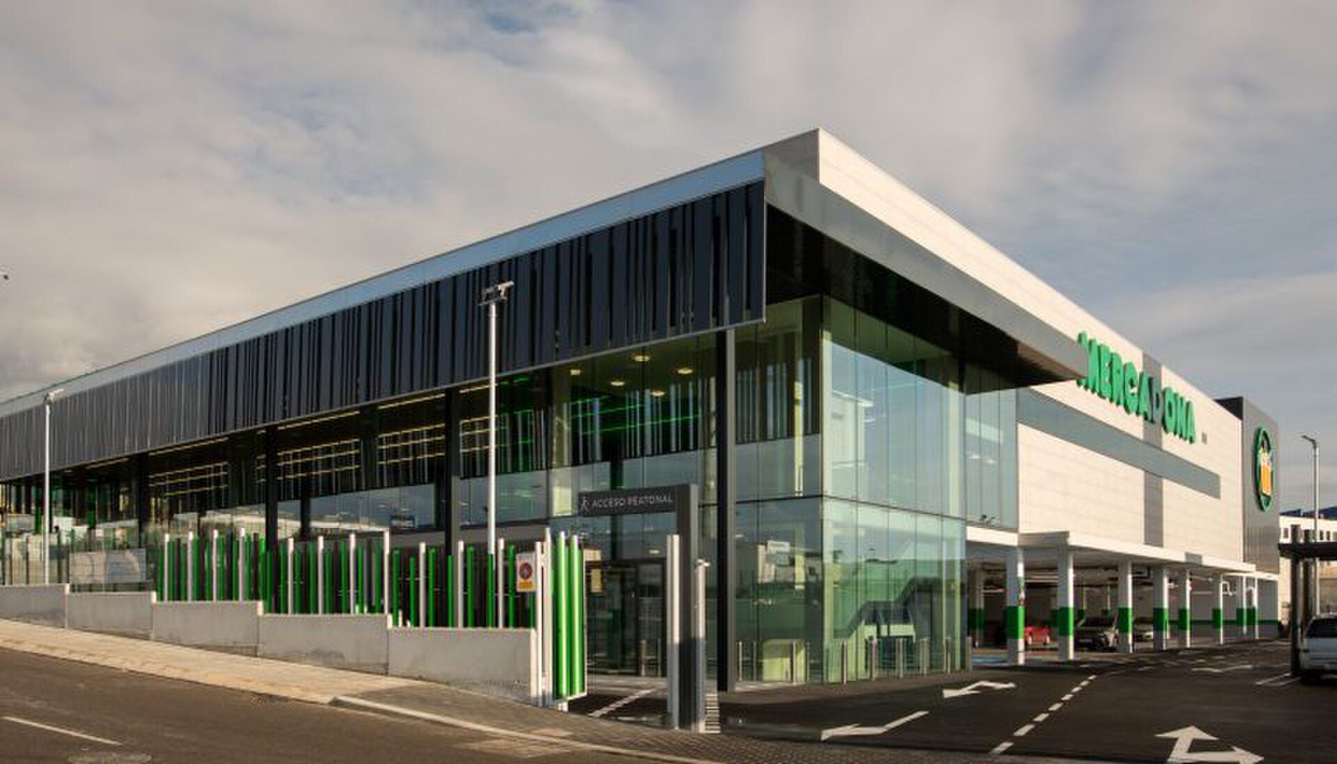 Modern building with glass facade, parking lot, and green accents.
