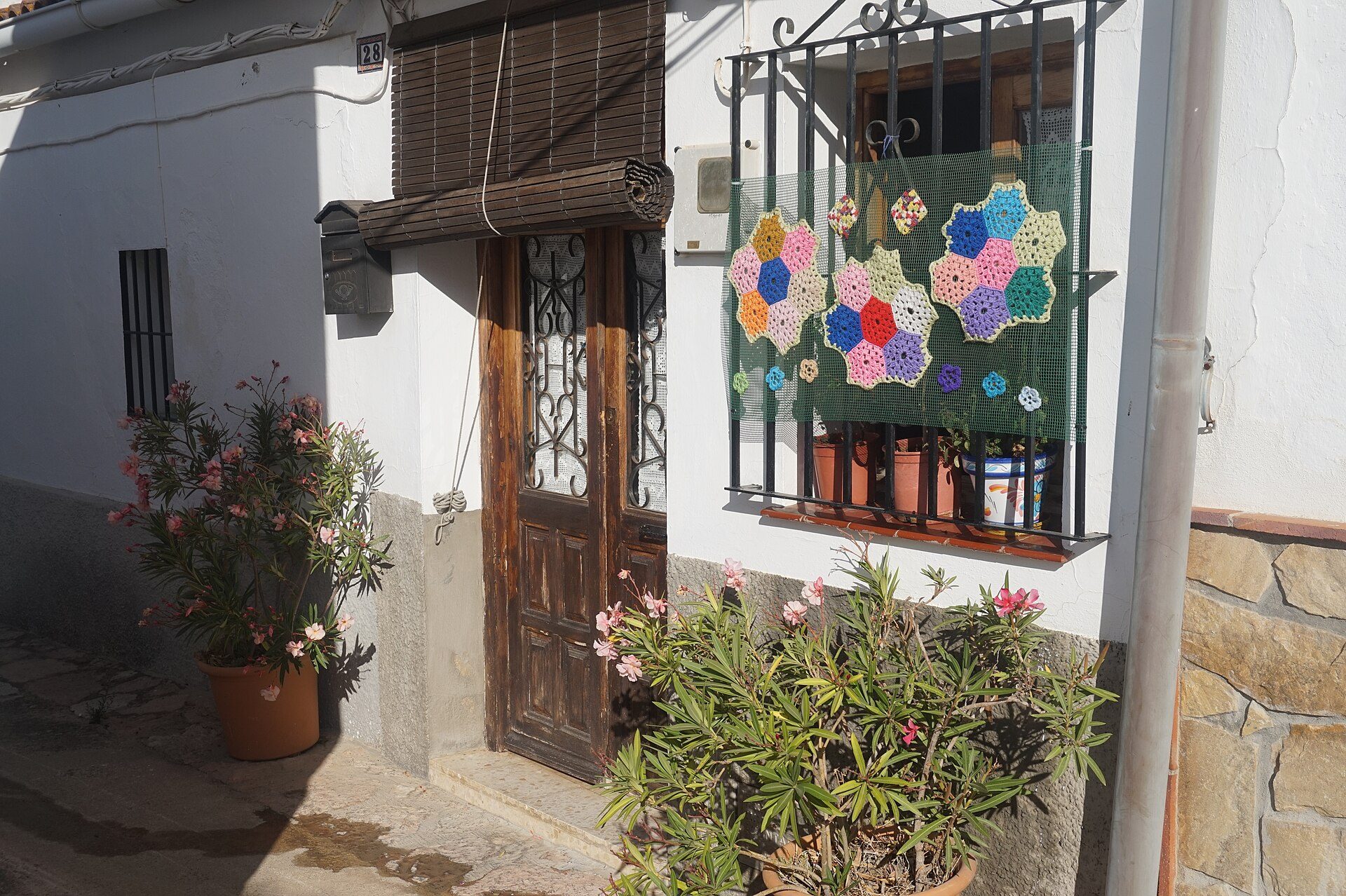 Cozy room with a view of a garden, featuring a wooden door and colorful crochet decorations.
