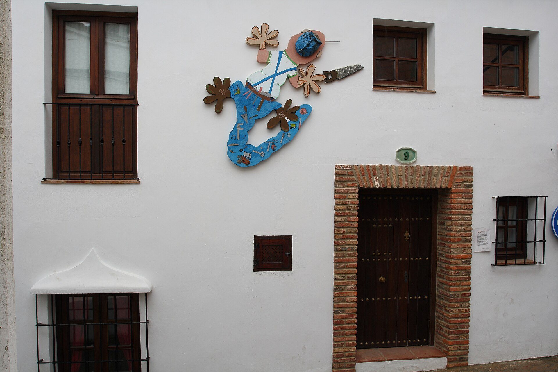Traditional white-walled room with wooden doors, decorative blue artwork, and small windows.