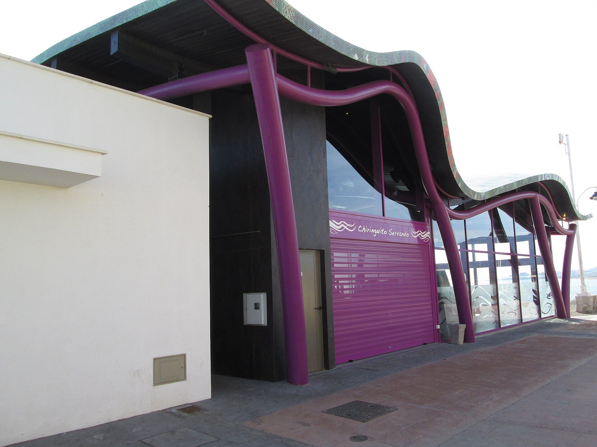 Modern building with purple accents, large windows, and a curved roof design.