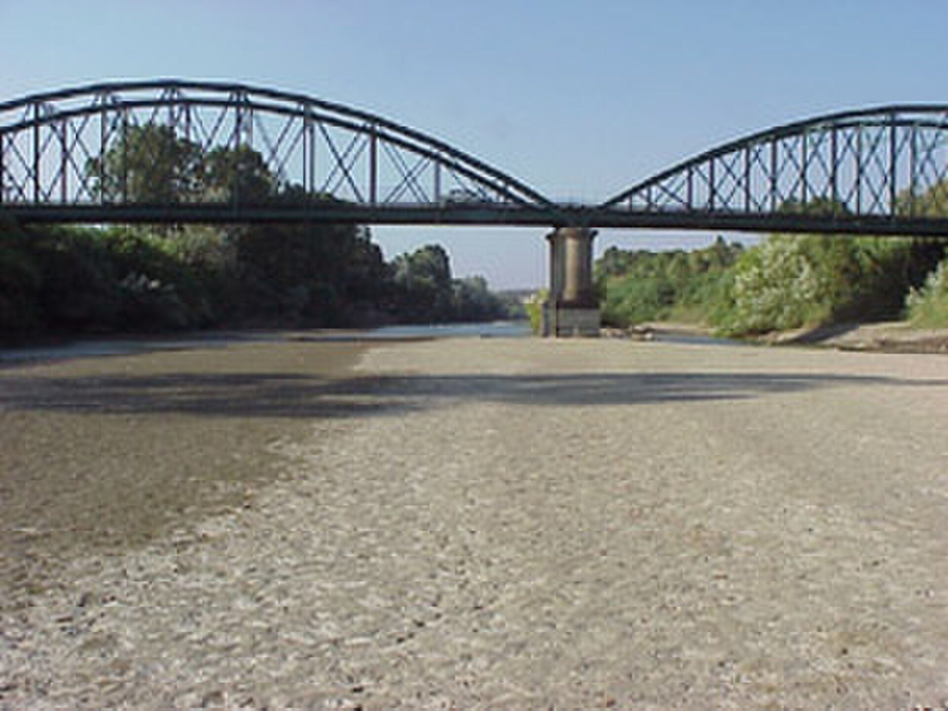 Alt text: River view with a metal bridge and lush greenery.