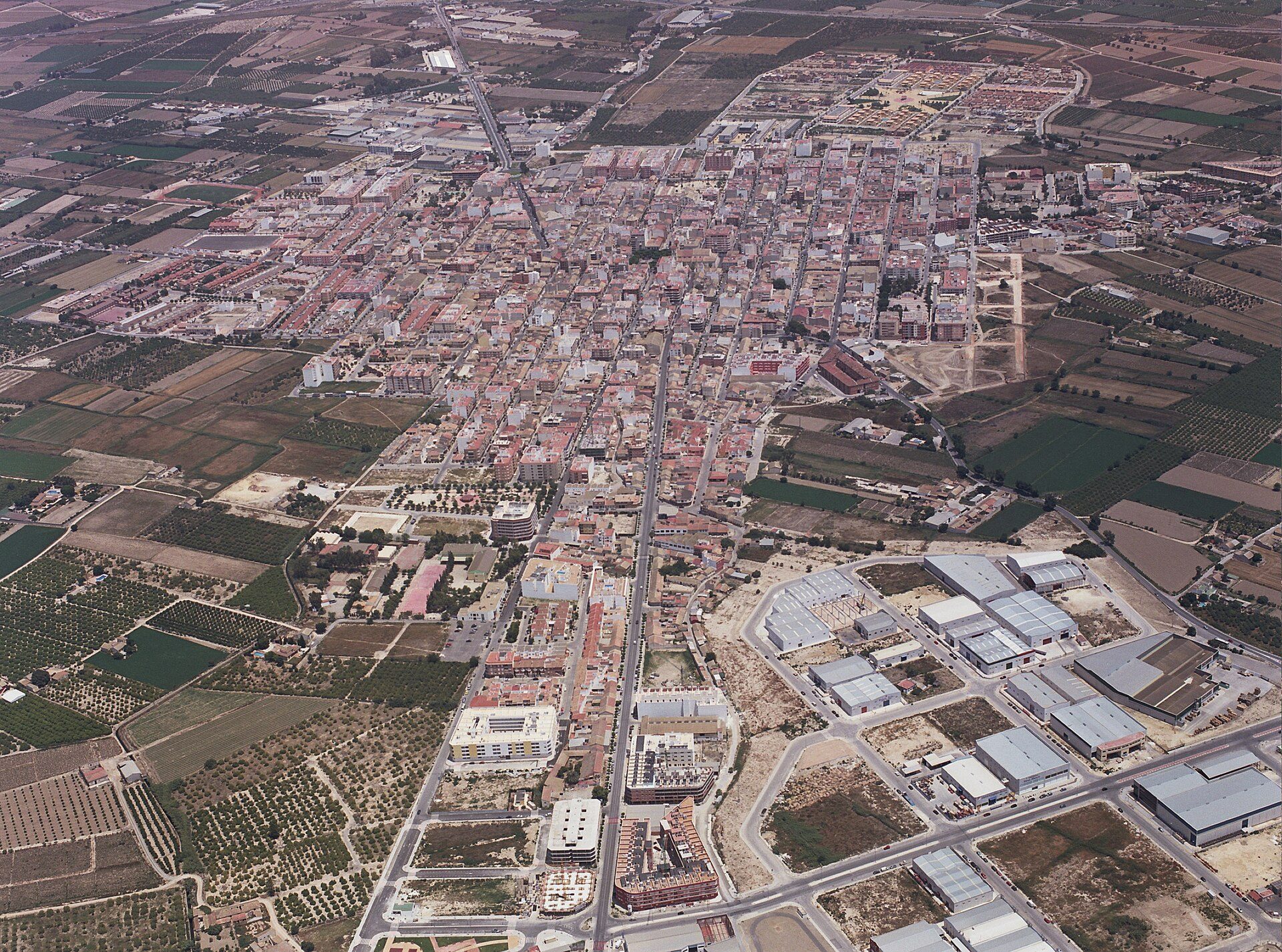 Aerial view of a town with dense buildings, surrounded by agricultural fields.