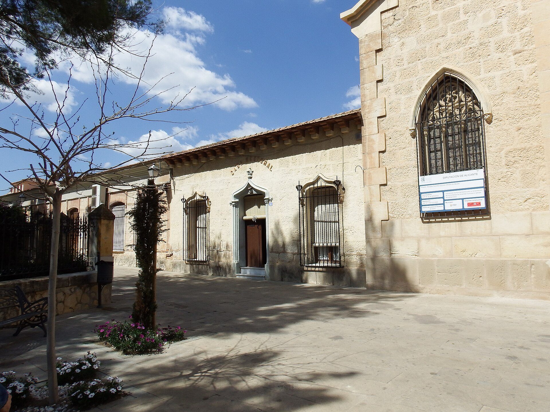 Alt text: Stone building with arched windows, courtyard, and clear blue sky.