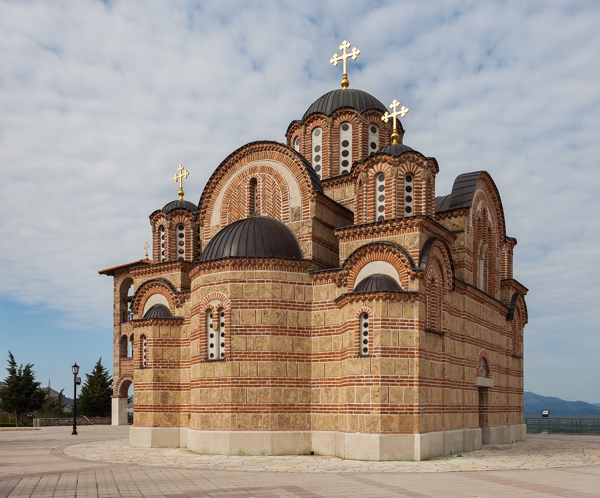 Alt text: Historic church with domes, brick facade, and cross, set against a clear sky.