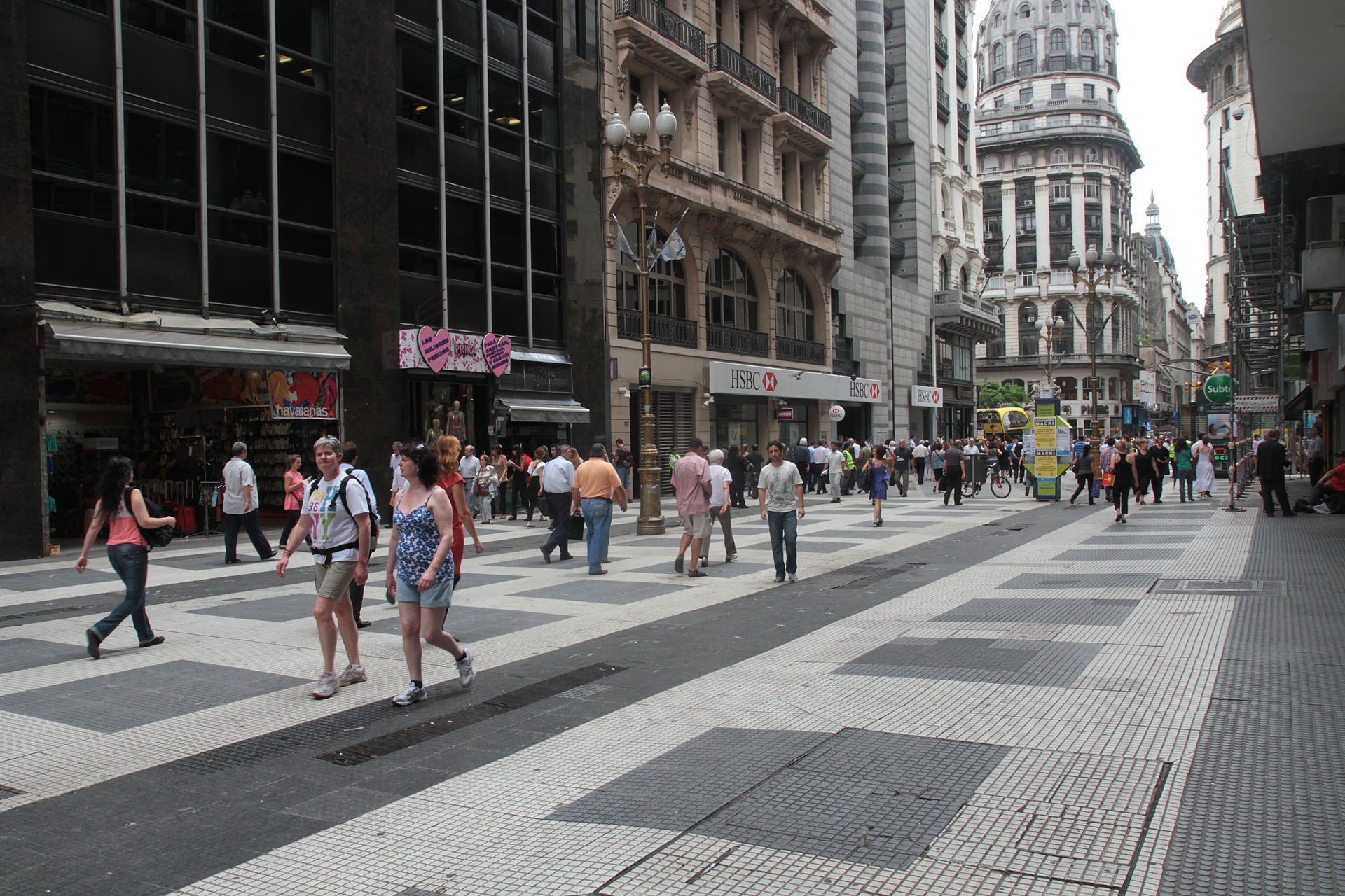 Alt text: City street scene with pedestrians, shops, and historic buildings.