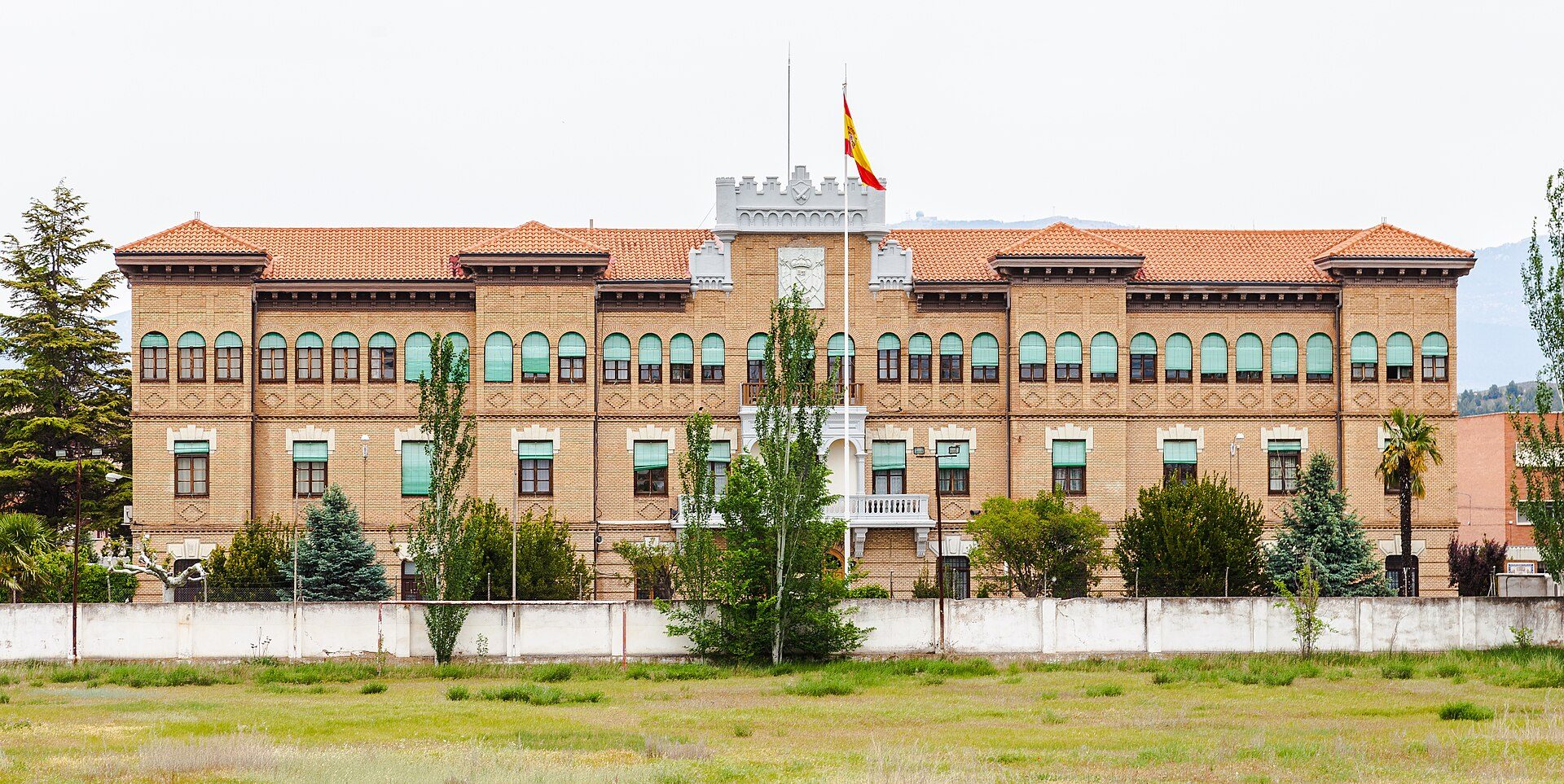 A large, historic building with a courtyard, featuring multiple windows and a central flagpole.