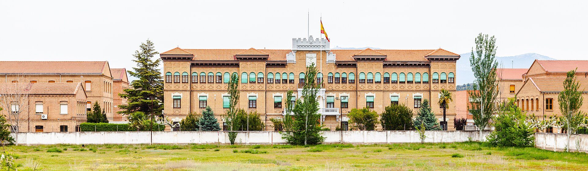 Traditional building with large windows, central tower, and Spanish flag.