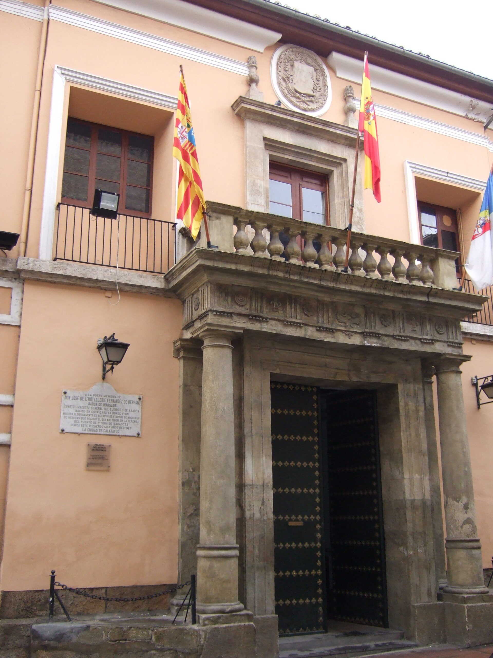 Alt text: Historic building with ornate entrance, flags, and plaque.