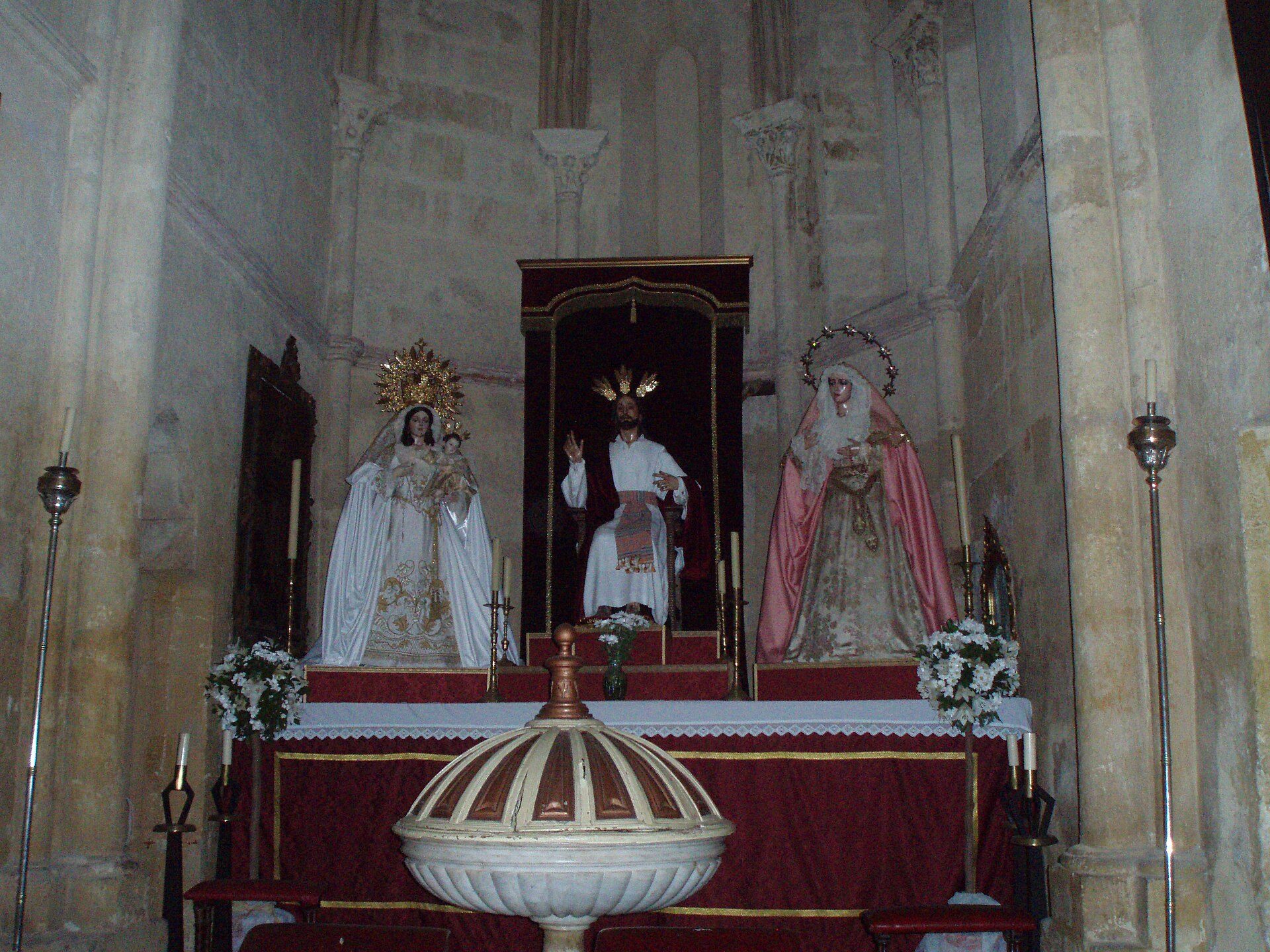 Altar in a church with statues of religious figures, candles, and ornate decorations.