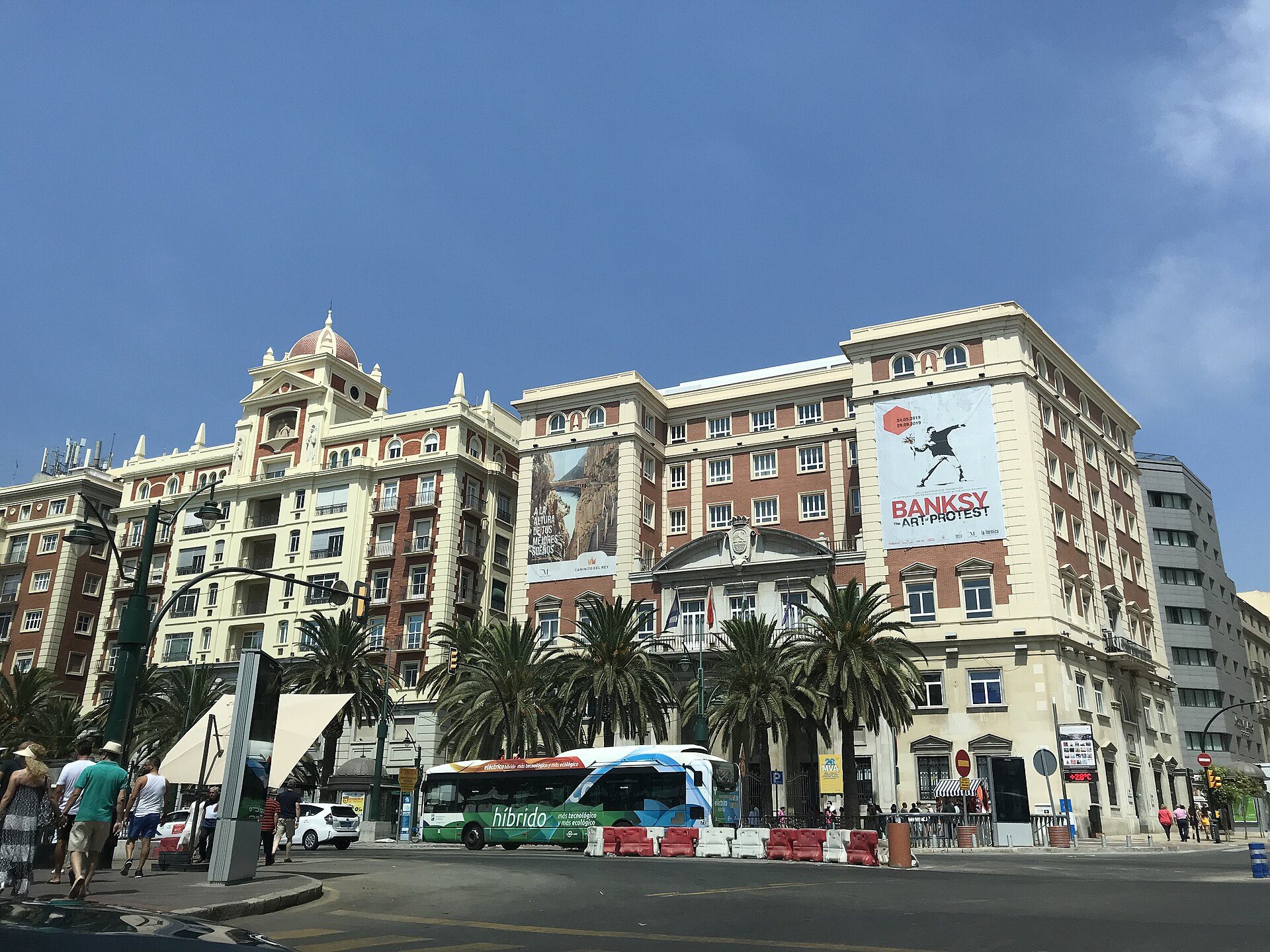 Luxurious hotel room with city view, featuring balcony, modern decor, and large windows.