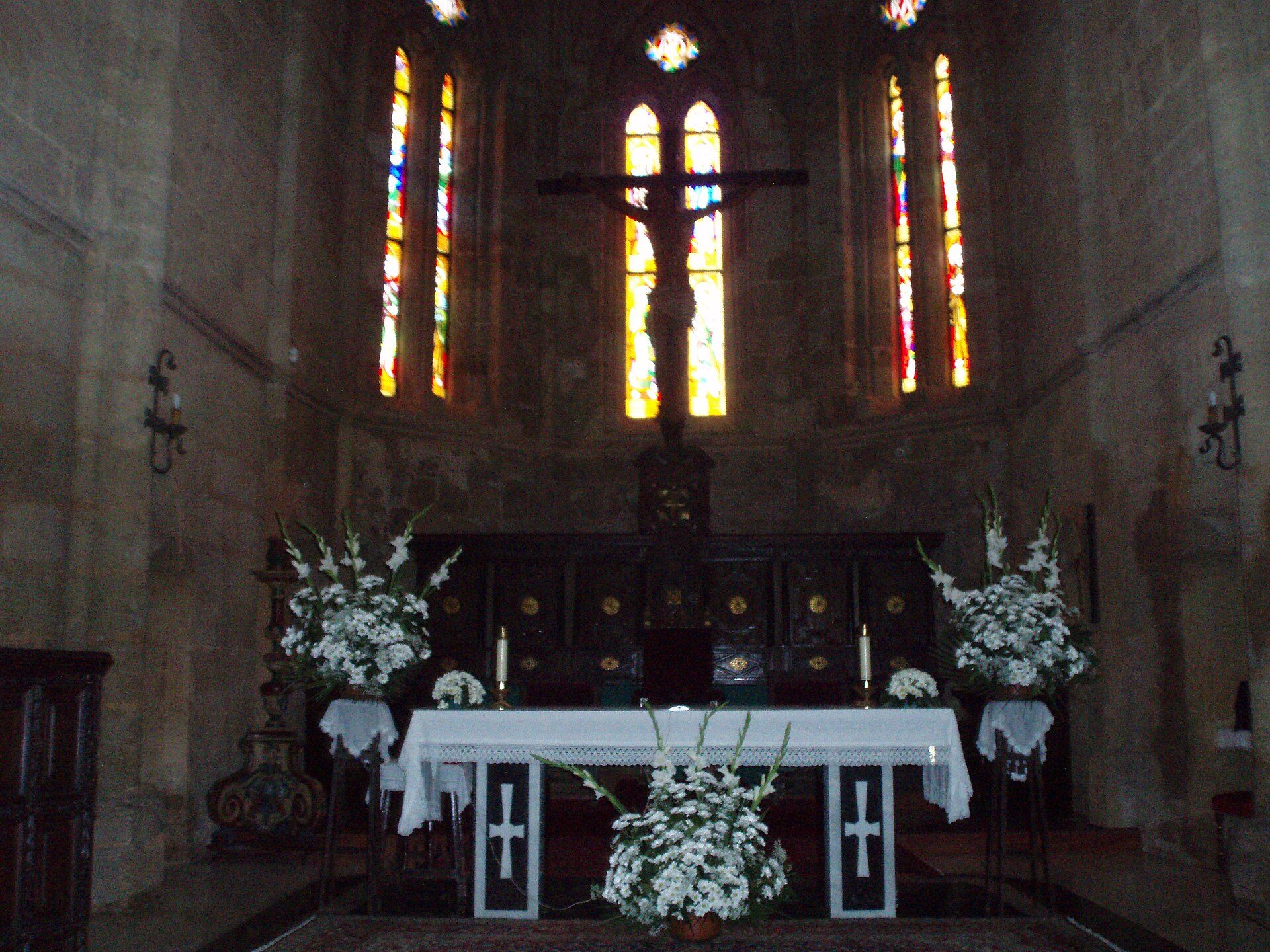 Alt text: Interior of a church with stained glass windows, altar, and floral arrangements.