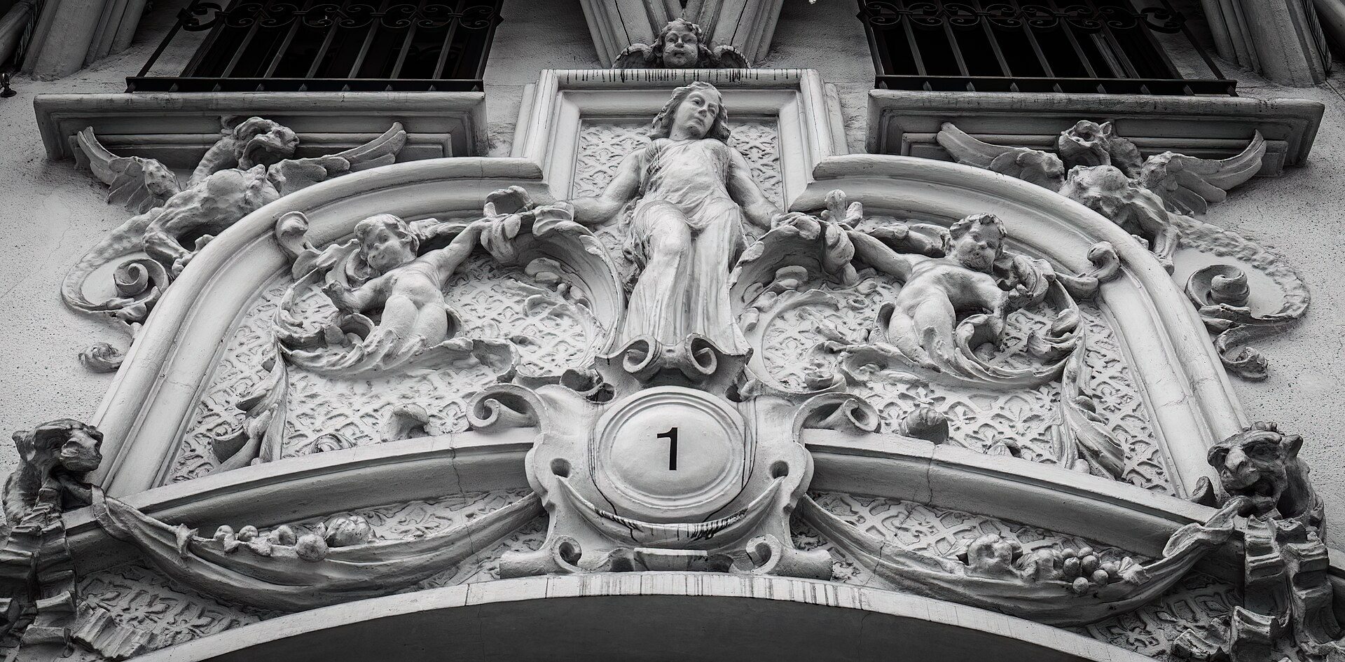 Intricate stone carving with angelic figures and a central figure, above a doorway.