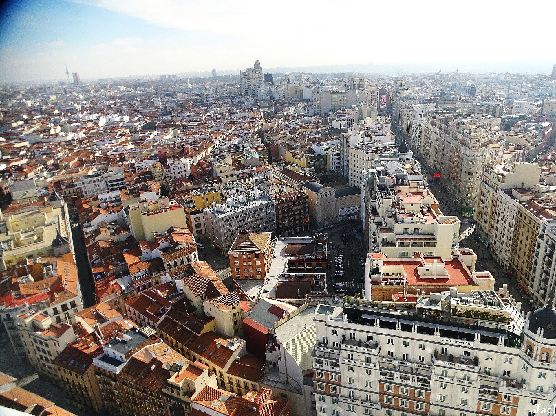 A spacious room with a panoramic city view, featuring large windows and modern decor.