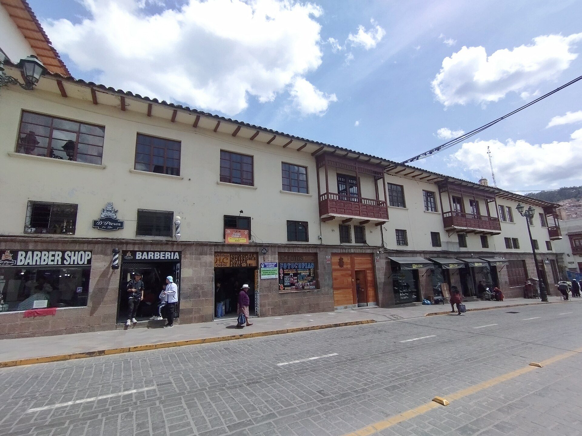 Two-story building with shops on the ground floor, balconies, and large windows.