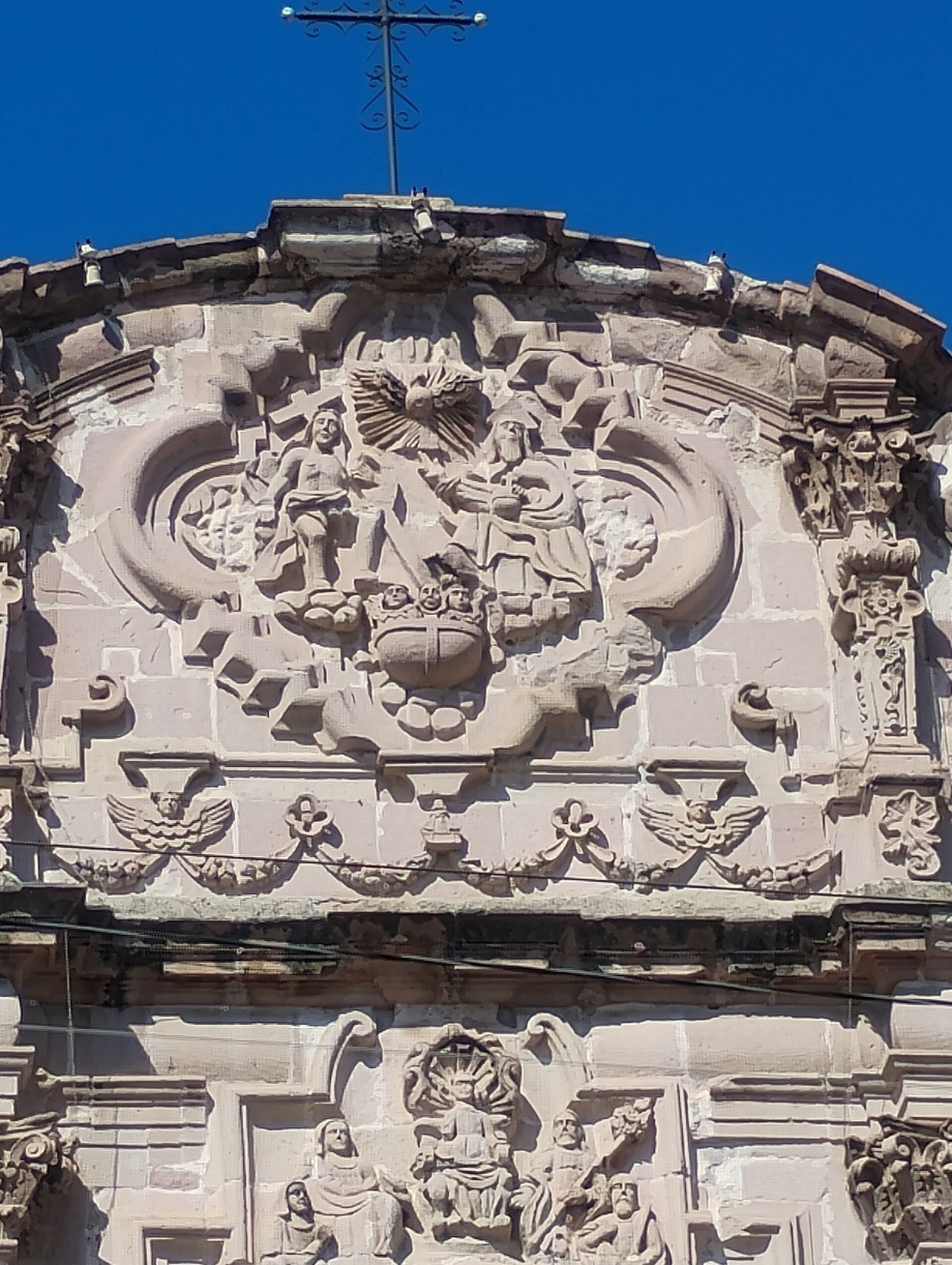 Alt text: Ornate stone facade with intricate carvings and a cross at the top.
