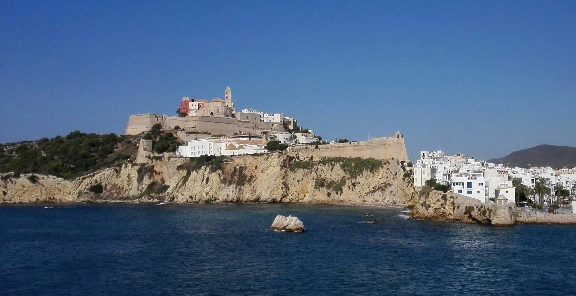 Coastal view from a cozy room with a balcony overlooking the sea and historic town.