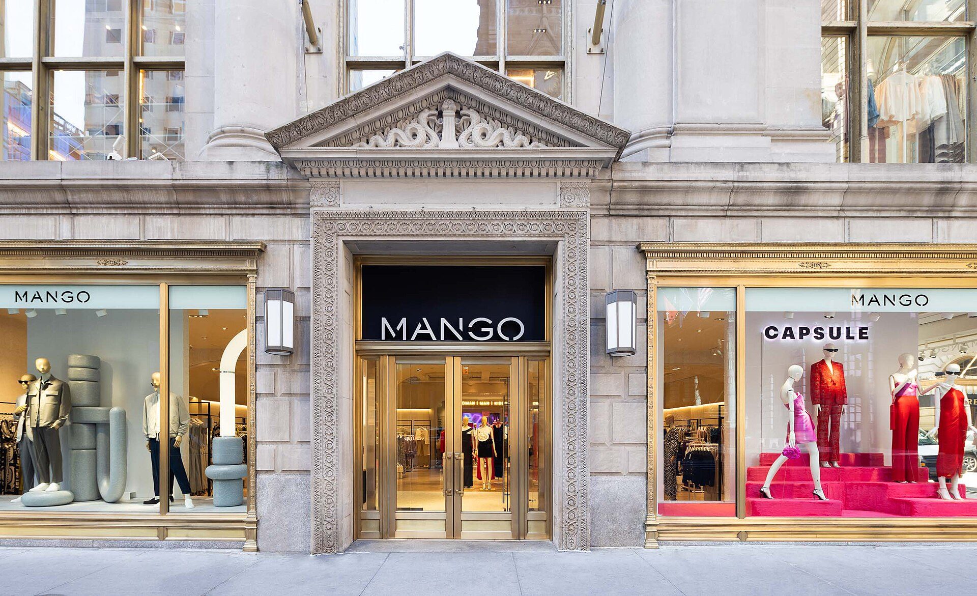 Storefront of MANGO with mannequins and clothing display, large windows, and entrance.