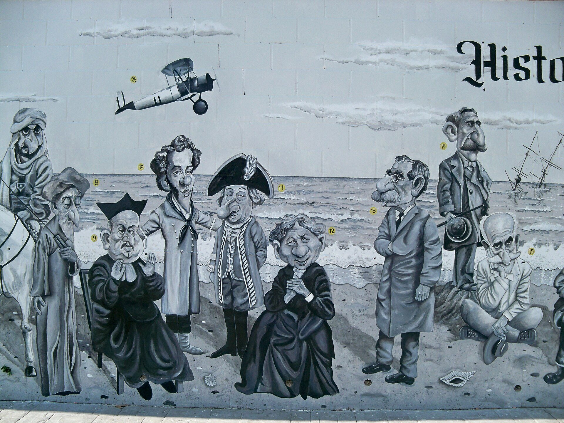 A mural depicting historical figures and a biplane, with a beach and ocean view.
