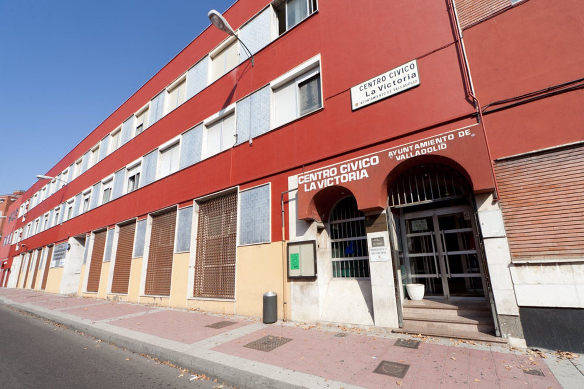 Red building with multiple windows, balconies, and a sign for "Centro Civico La Victoria.