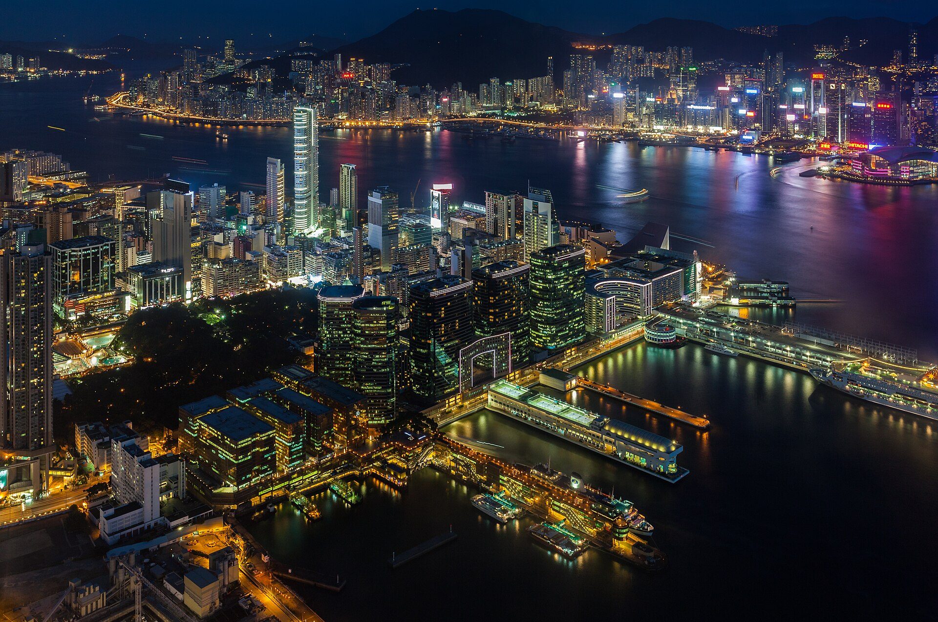 Aerial view of a cityscape at night with high-rise buildings and a harbor.