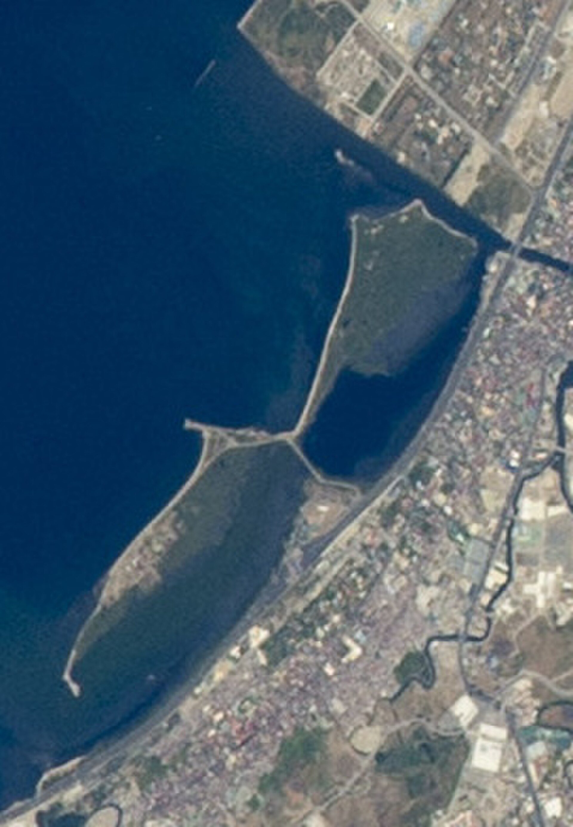 Aerial view of coastal cityscape with waterfront and urban development.