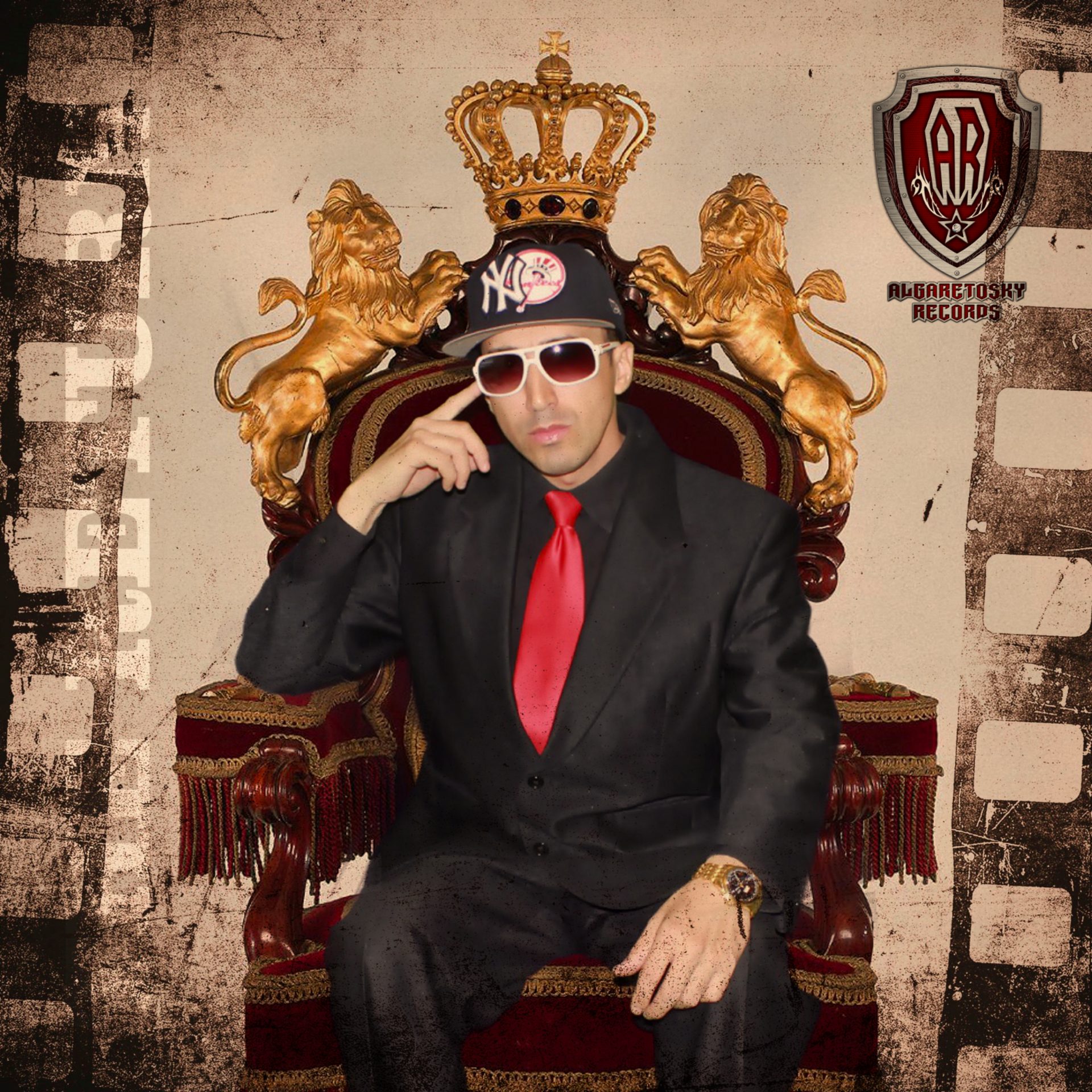 A man in a black suit and red tie sits on a throne-like chair with a crown and lion statues.