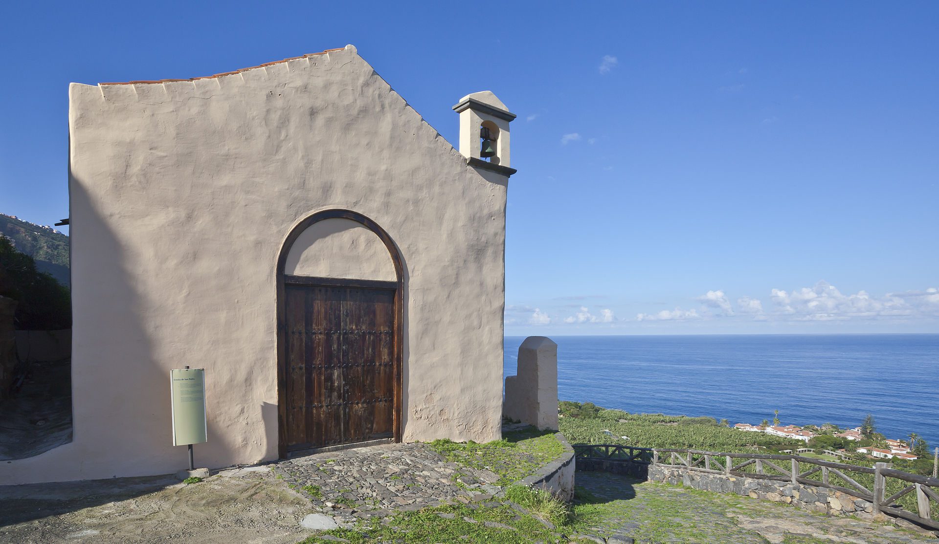 Cozy room with ocean view, wooden door, stone walls, and small bell tower.