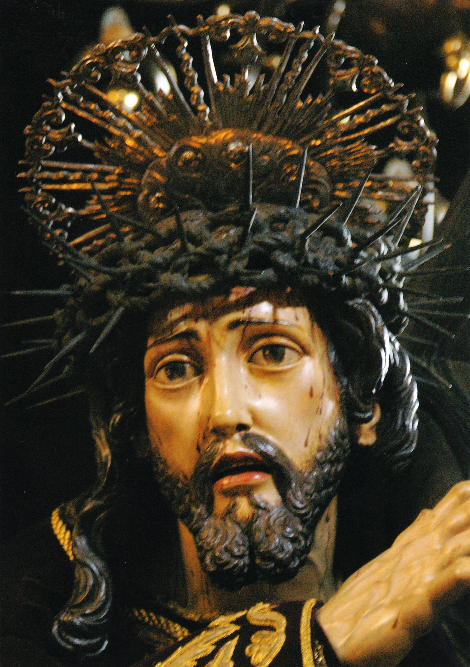 A detailed statue of a bearded figure with a crown of thorns, set against a dark background.