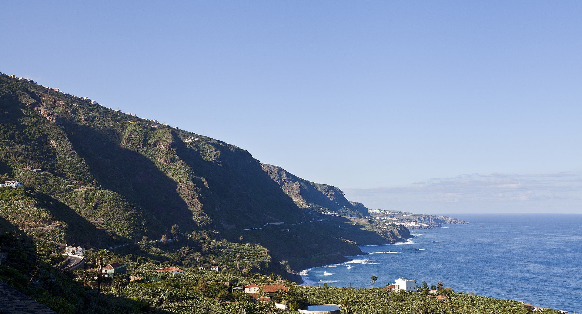 Cozy room with ocean view, balcony, and mountain backdrop.