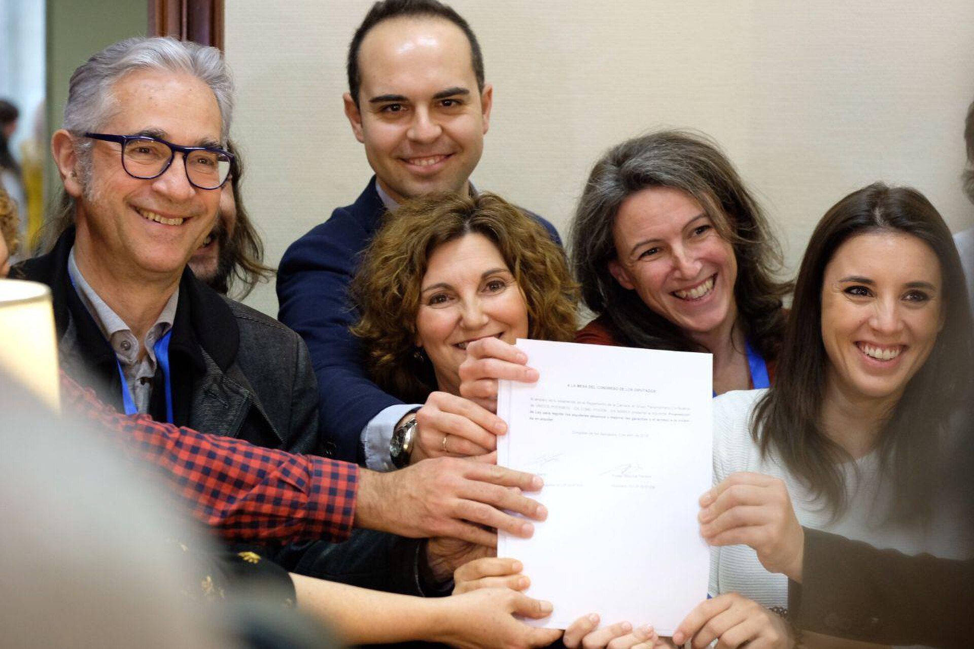 A group of people smiling and holding a document in a conference room.