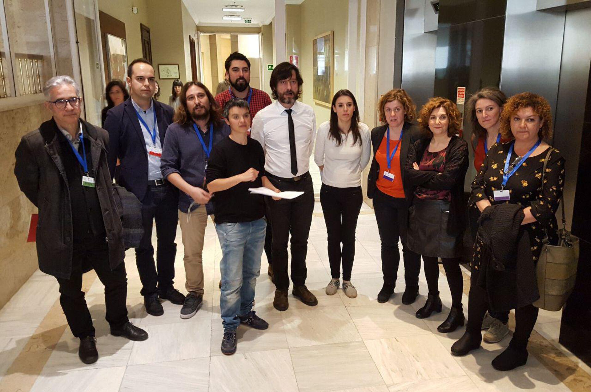 A group of people posing for a photo in a hallway with marble floors and modern decor.